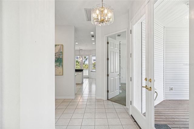 corridor with light tile patterned floors and a notable chandelier