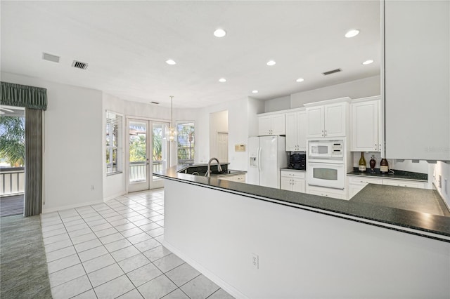 kitchen featuring kitchen peninsula, white appliances, white cabinetry, hanging light fixtures, and light tile patterned flooring