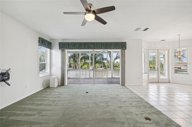 unfurnished living room featuring light carpet, french doors, and ceiling fan with notable chandelier