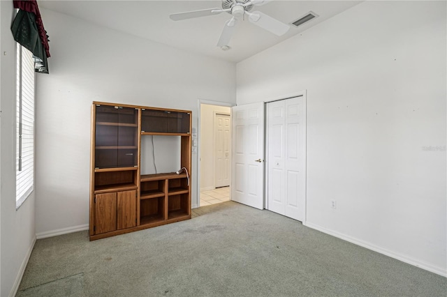 unfurnished bedroom featuring a closet, light colored carpet, and ceiling fan