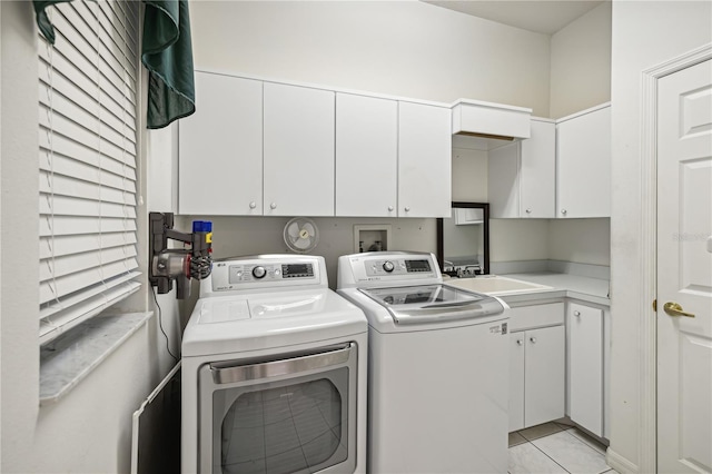 washroom with washing machine and clothes dryer, sink, light tile patterned floors, and cabinets