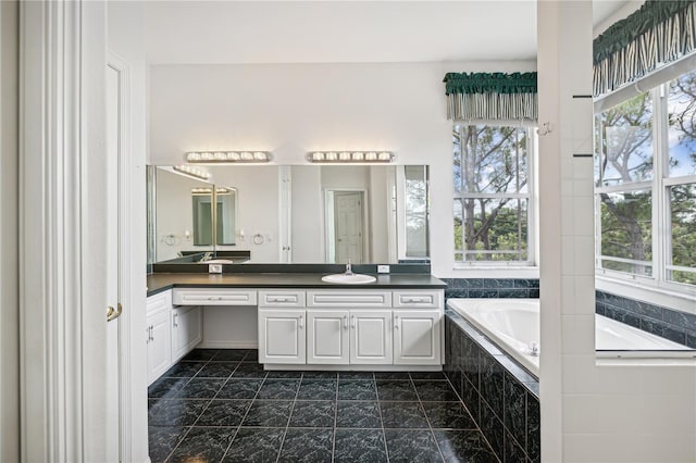 bathroom featuring vanity, tiled bath, tile patterned floors, and a healthy amount of sunlight