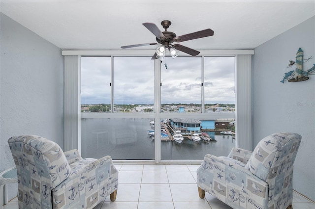 sitting room with floor to ceiling windows, a water view, light tile patterned flooring, and ceiling fan