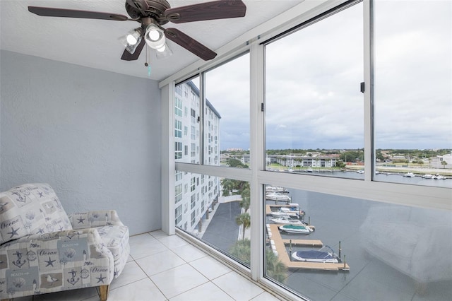 sunroom featuring ceiling fan and a water view