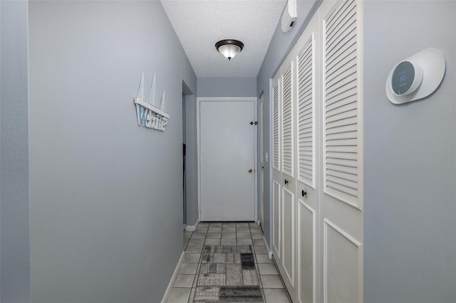 hallway featuring light tile patterned flooring and a textured ceiling