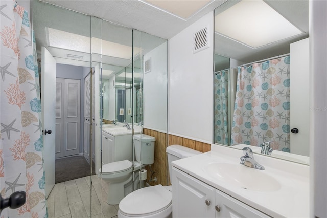 bathroom with vanity, wooden walls, and toilet