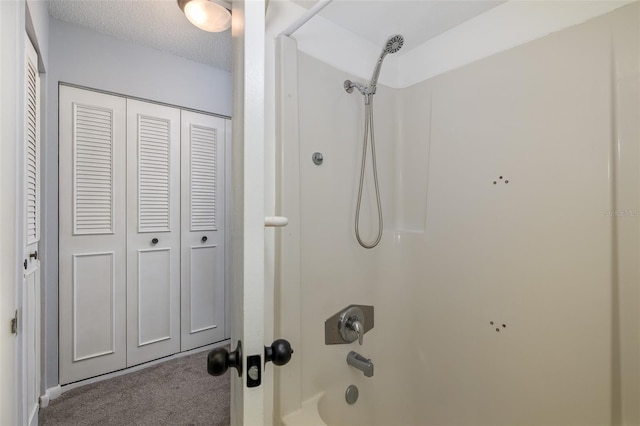 bathroom with washtub / shower combination and a textured ceiling