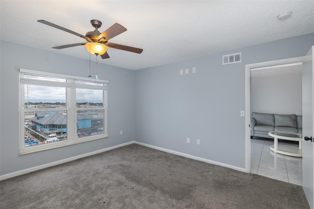 unfurnished room with ceiling fan, light colored carpet, and a textured ceiling