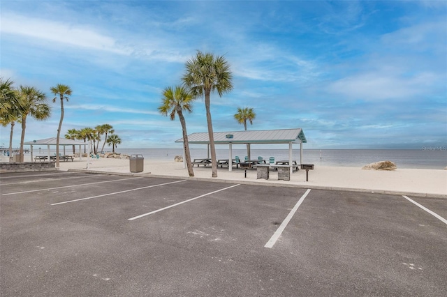 view of parking / parking lot with a gazebo, a water view, and a beach view