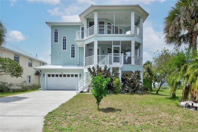 coastal home featuring a garage, a balcony, and a front lawn