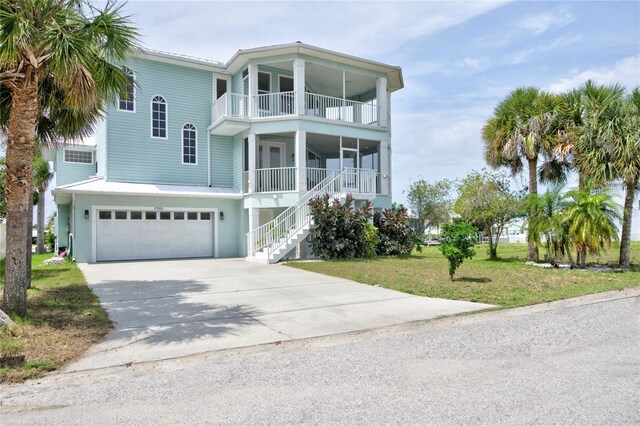 coastal home featuring a garage, a front yard, and a balcony