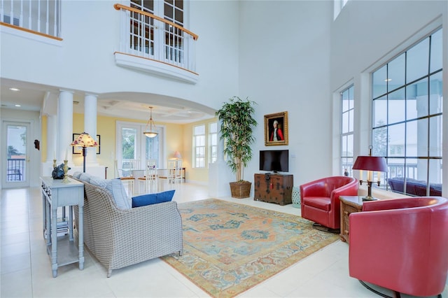 tiled living room featuring decorative columns and a towering ceiling