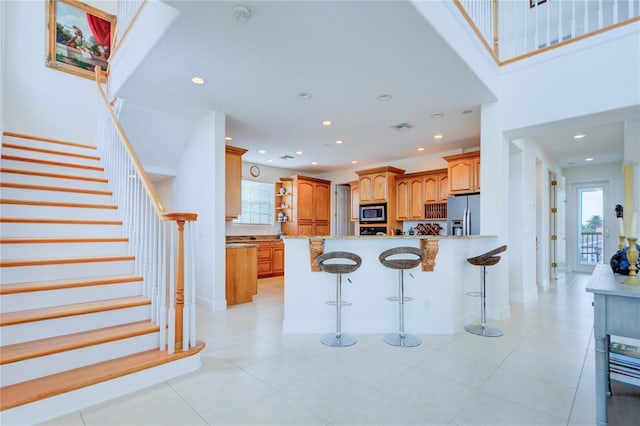 kitchen with a wealth of natural light, kitchen peninsula, a kitchen breakfast bar, and stainless steel appliances