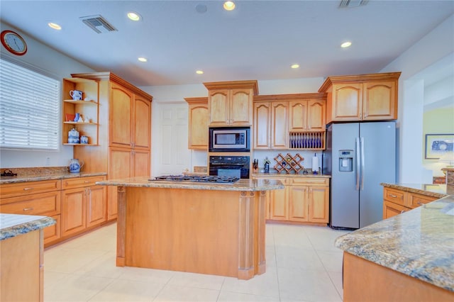 kitchen featuring a center island, light brown cabinets, stainless steel appliances, light stone counters, and light tile patterned floors