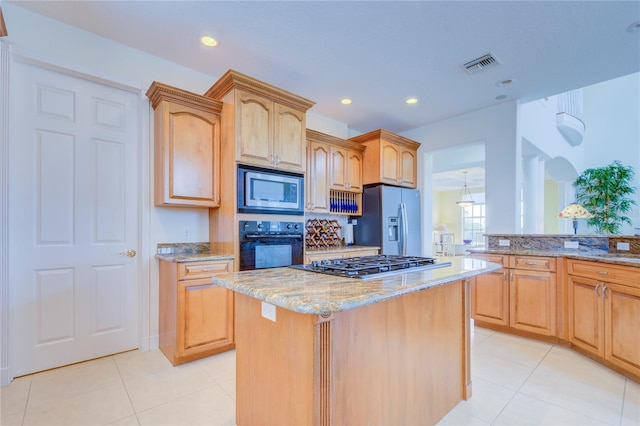 kitchen featuring appliances with stainless steel finishes, tasteful backsplash, light tile patterned flooring, a kitchen island, and light stone counters