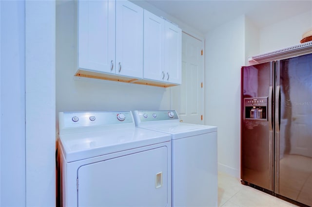 washroom with light tile patterned flooring, washer and dryer, and cabinets