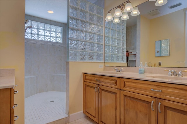 bathroom with vanity, tile patterned flooring, and a tile shower