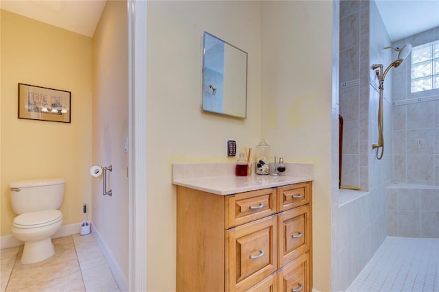 bathroom featuring toilet, vanity, tiled shower, and tile patterned flooring