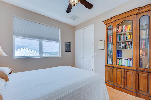 bedroom featuring light wood-type flooring, ceiling fan, and a closet