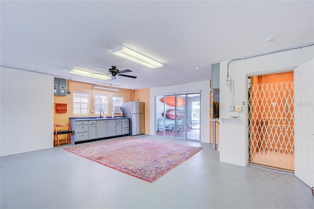 interior space featuring a textured ceiling, ceiling fan, concrete flooring, and sink