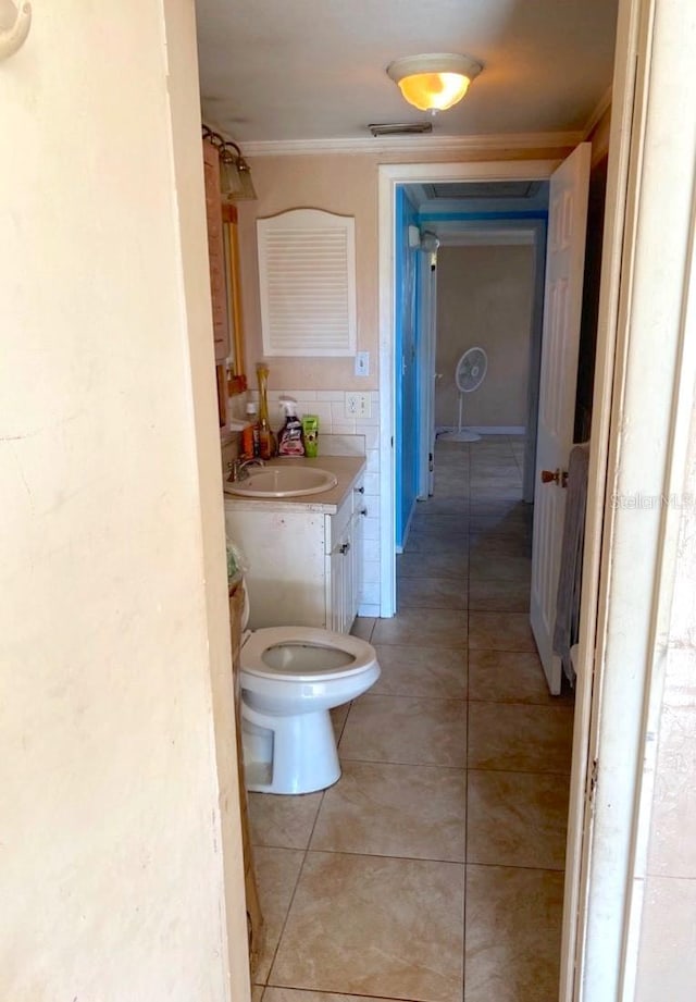 bathroom with tile patterned floors, toilet, vanity, and ornamental molding