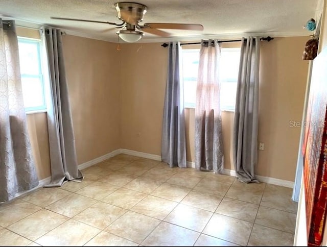 spare room with ceiling fan, light tile patterned floors, and a textured ceiling