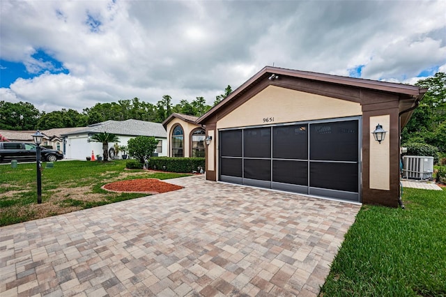 view of front facade with central AC unit, a garage, and a front yard