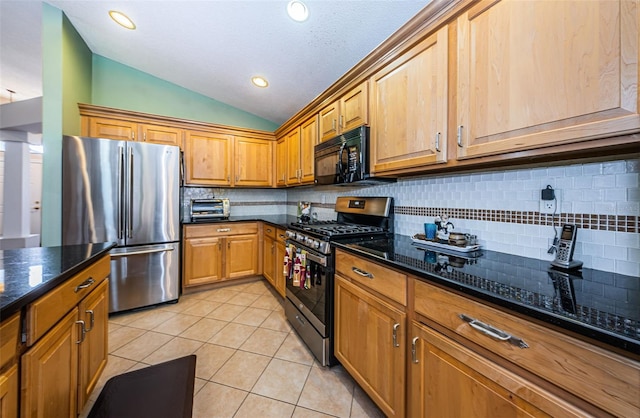 kitchen featuring lofted ceiling, decorative backsplash, dark stone countertops, light tile patterned floors, and stainless steel appliances