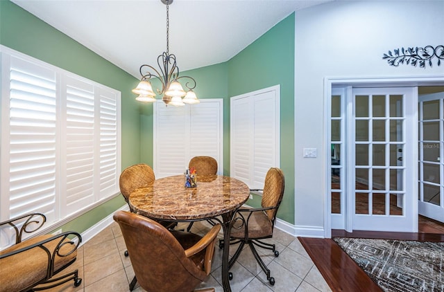 dining area featuring a notable chandelier, light tile patterned flooring, and vaulted ceiling