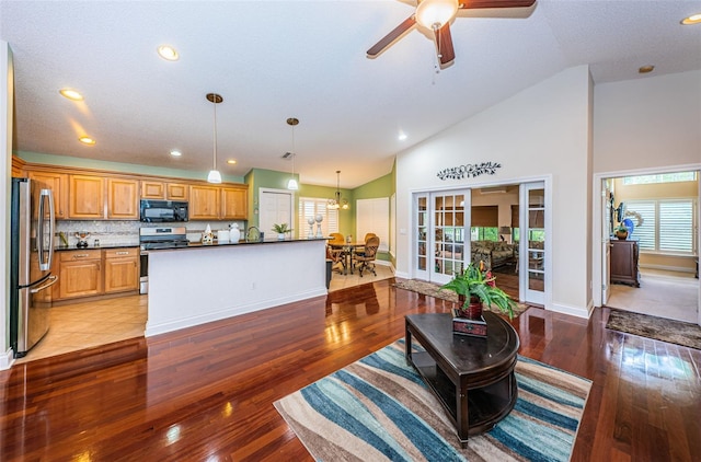 living room with high vaulted ceiling, ceiling fan with notable chandelier, sink, light wood-type flooring, and a textured ceiling