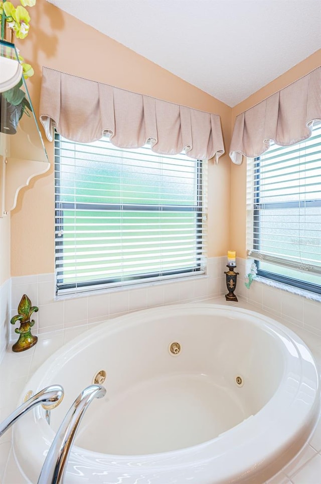 bathroom with vaulted ceiling and tiled tub