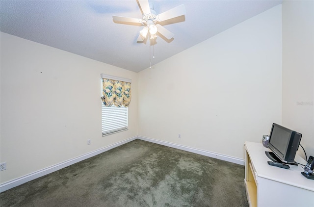 unfurnished office with ceiling fan, dark carpet, and vaulted ceiling