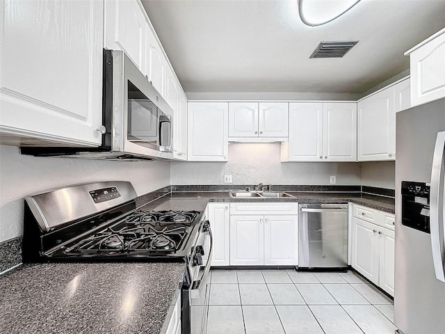 kitchen with white cabinets, appliances with stainless steel finishes, light tile patterned flooring, and sink