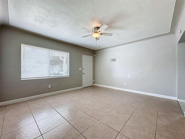 spare room featuring a ceiling fan, a textured ceiling, visible vents, baseboards, and light tile patterned flooring