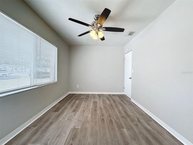 unfurnished room featuring baseboards, ceiling fan, wood finished floors, and visible vents