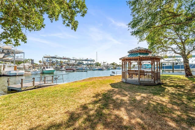 view of dock with a gazebo, a yard, and a water view