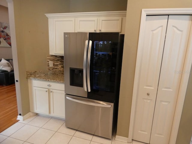 kitchen featuring white cabinets, light stone counters, stainless steel fridge with ice dispenser, and backsplash