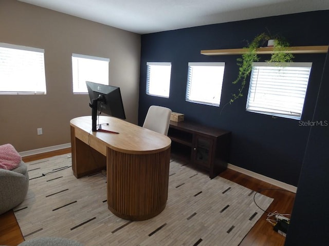 office with light hardwood / wood-style flooring and a healthy amount of sunlight