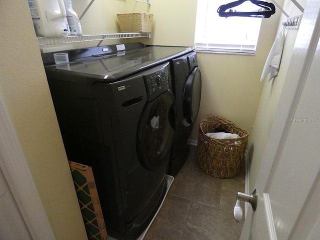 clothes washing area featuring separate washer and dryer and dark tile patterned flooring