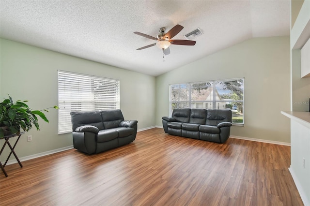 living room with plenty of natural light, wood-type flooring, and lofted ceiling