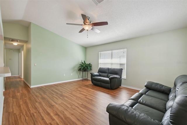 living room featuring ceiling fan, wood-type flooring, a textured ceiling, and lofted ceiling