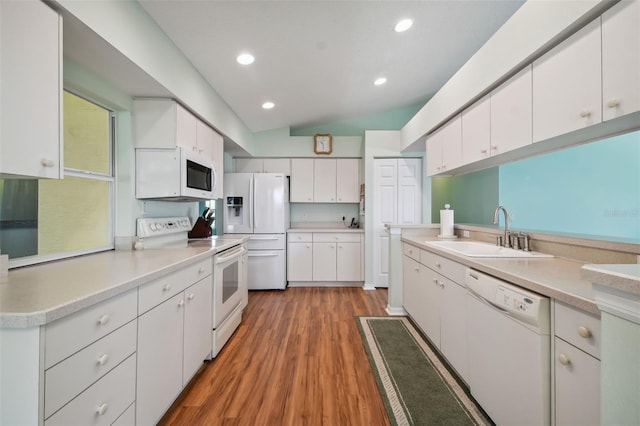 kitchen with white cabinetry, sink, hardwood / wood-style floors, vaulted ceiling, and white appliances