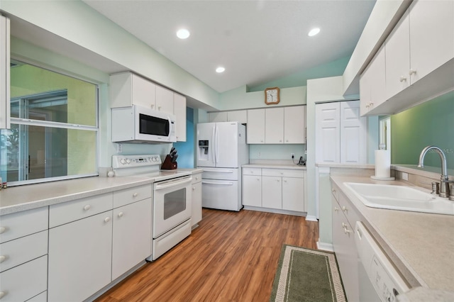 kitchen featuring white appliances, sink, hardwood / wood-style flooring, white cabinets, and lofted ceiling