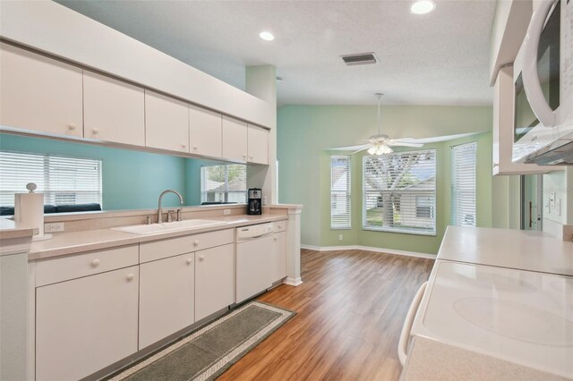 kitchen featuring white appliances, white cabinetry, lofted ceiling, and sink