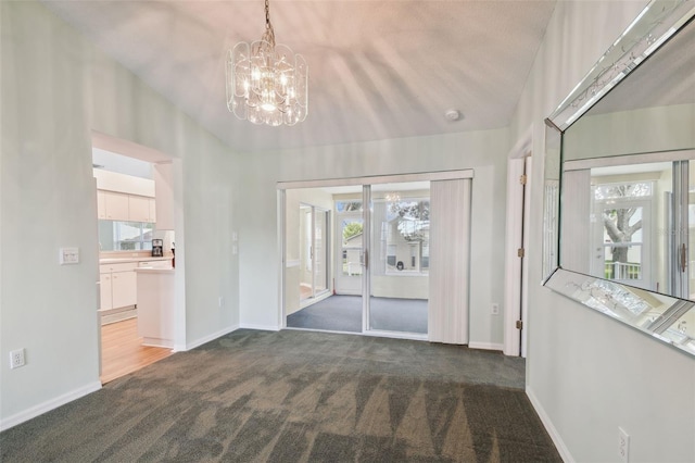 interior space featuring a chandelier, a healthy amount of sunlight, and dark carpet