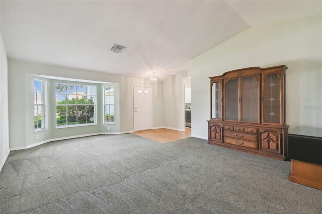 unfurnished living room with carpet flooring and lofted ceiling