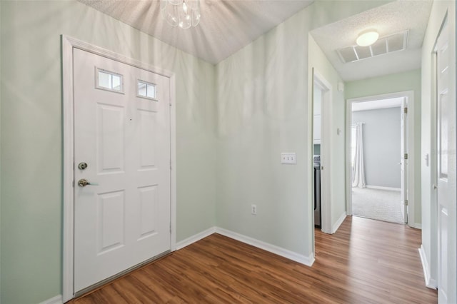 foyer entrance featuring a textured ceiling, hardwood / wood-style flooring, and an inviting chandelier