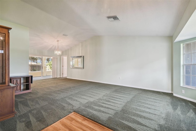 unfurnished living room with a chandelier, dark carpet, and lofted ceiling