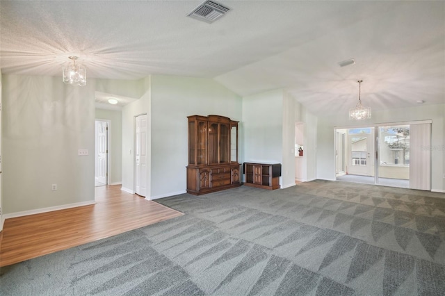 unfurnished living room featuring hardwood / wood-style flooring, vaulted ceiling, and a chandelier