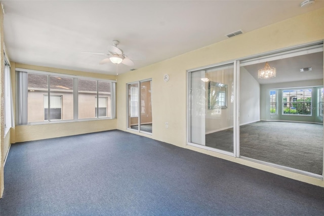 unfurnished sunroom featuring ceiling fan with notable chandelier